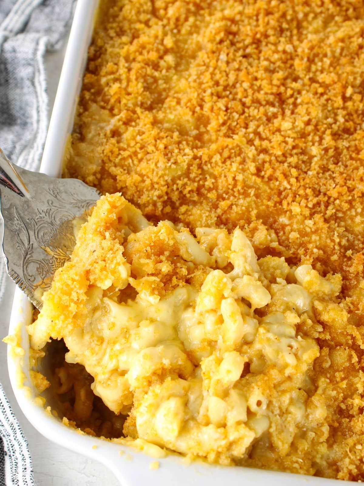 Creamy baked mac and cheese with golden panko breadcrumb topping being scooped from a white casserole dish