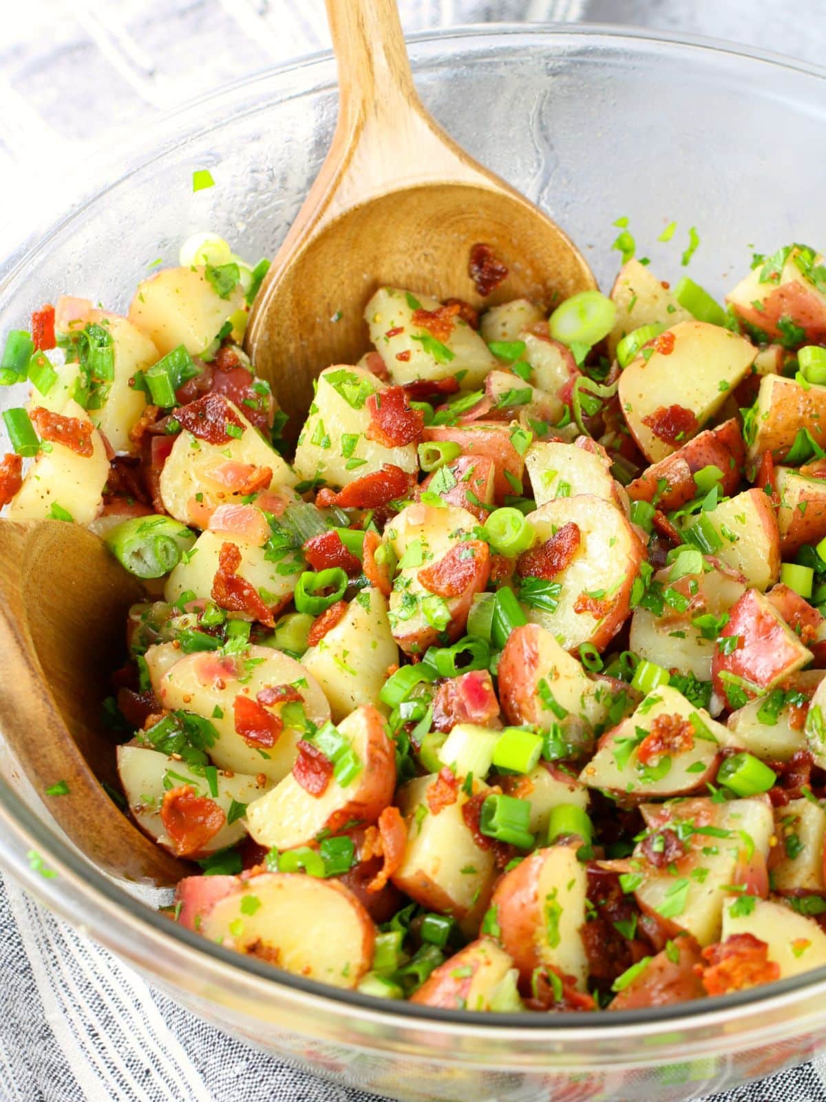 German potato salad with red baby potatoes, crispy bacon, onion, and a warm tangy vinegar-mustard dressing in a large bowl
