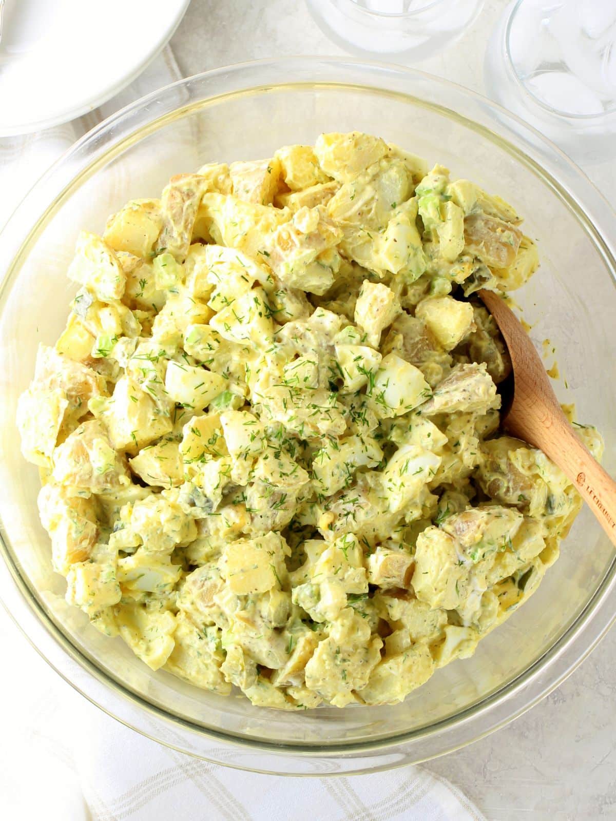 Instant Pot potato salad with eggs, celery, and a creamy mustard dressing in a white bowl — a hearty make-ahead BBQ side dish
