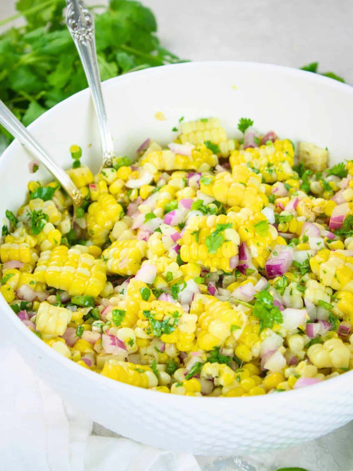 Jalapeño cilantro Mexican corn salad with red onion, jalapeno, cilantro, red wine vinegar and honey in a white bowl — a popular BBQ side dish recipe