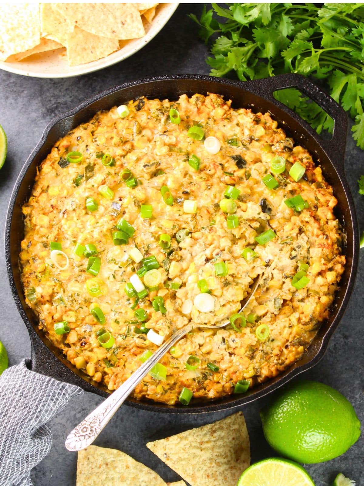 Smoky poblano corn dip in a cast iron skillet with tortilla chips — a creamy summer BBQ appetizer with charred corn and grilled poblanos