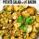 Smoky salt and vinegar potato salad with bacon, green onions, and parsley in a white serving bowl.
