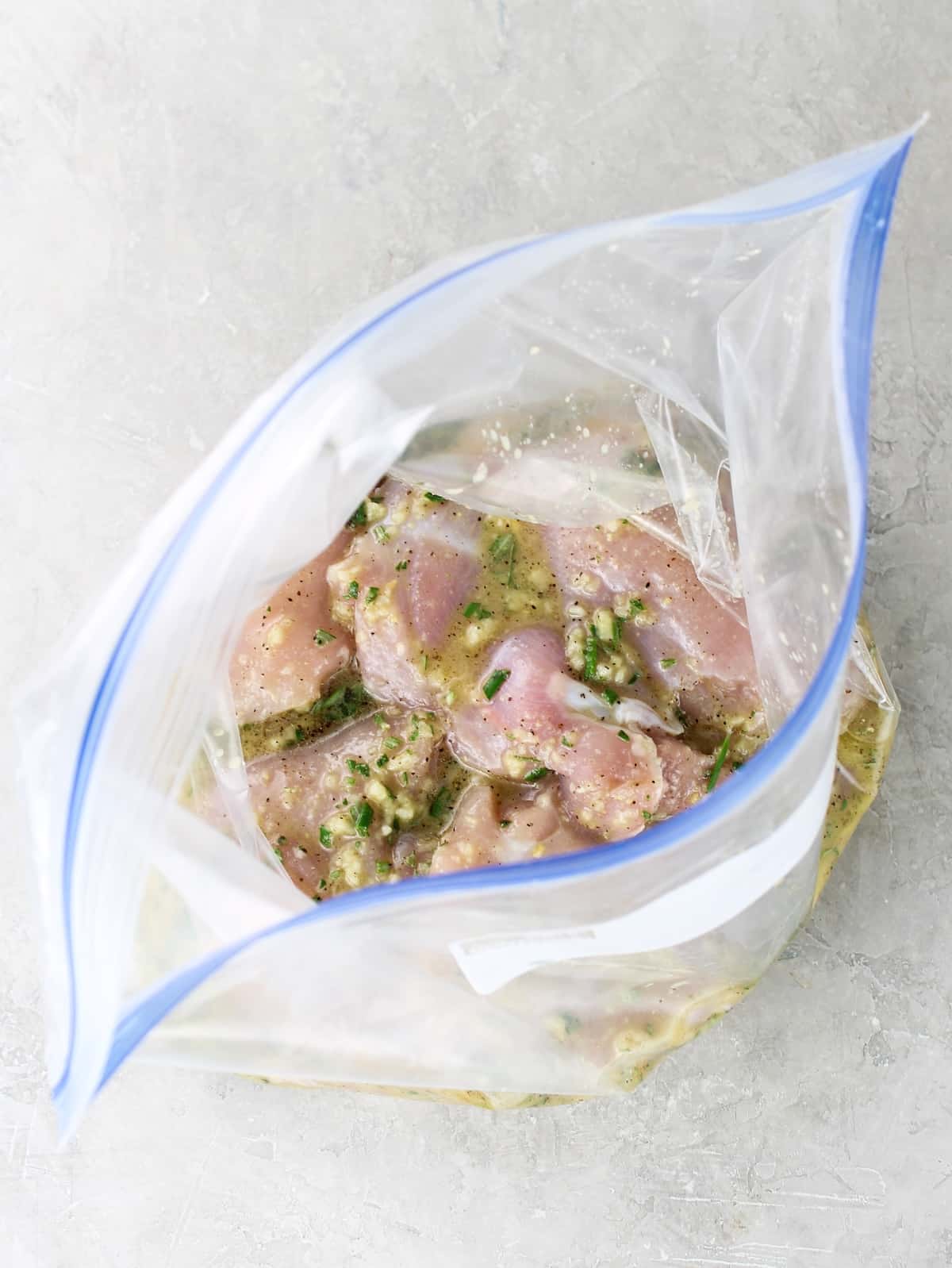 Boneless chicken thighs marinating in a zip-top bag with rosemary lemon honey marinade