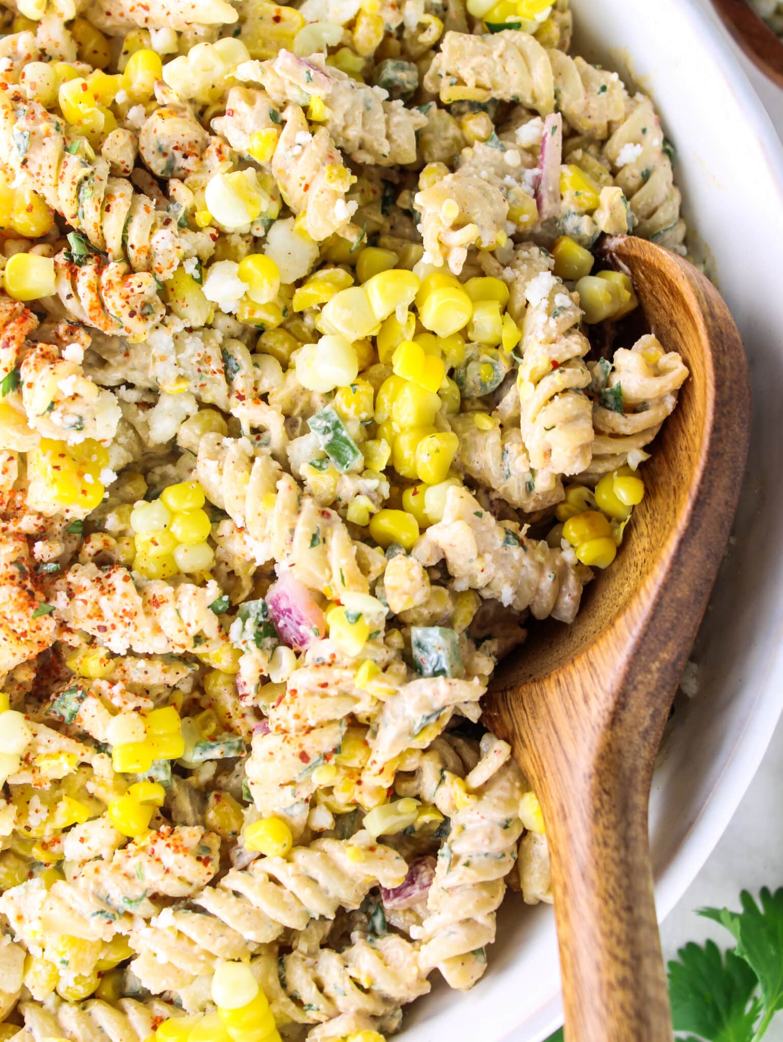 Close-up of elote pasta salad with rotini coated in creamy chili-lime dressing, corn, and cotija