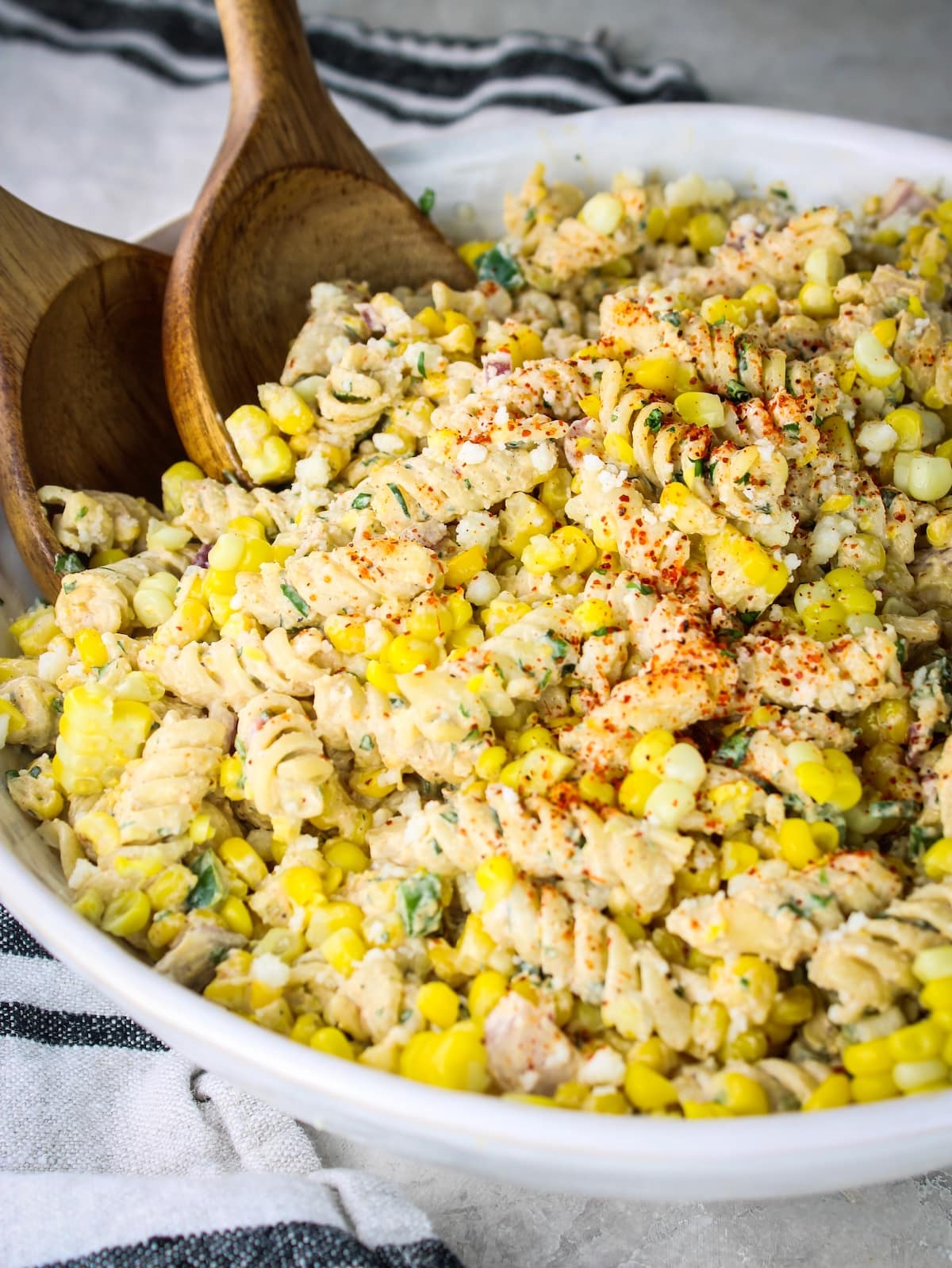 Angled view of elote pasta salad with two wooden spoons