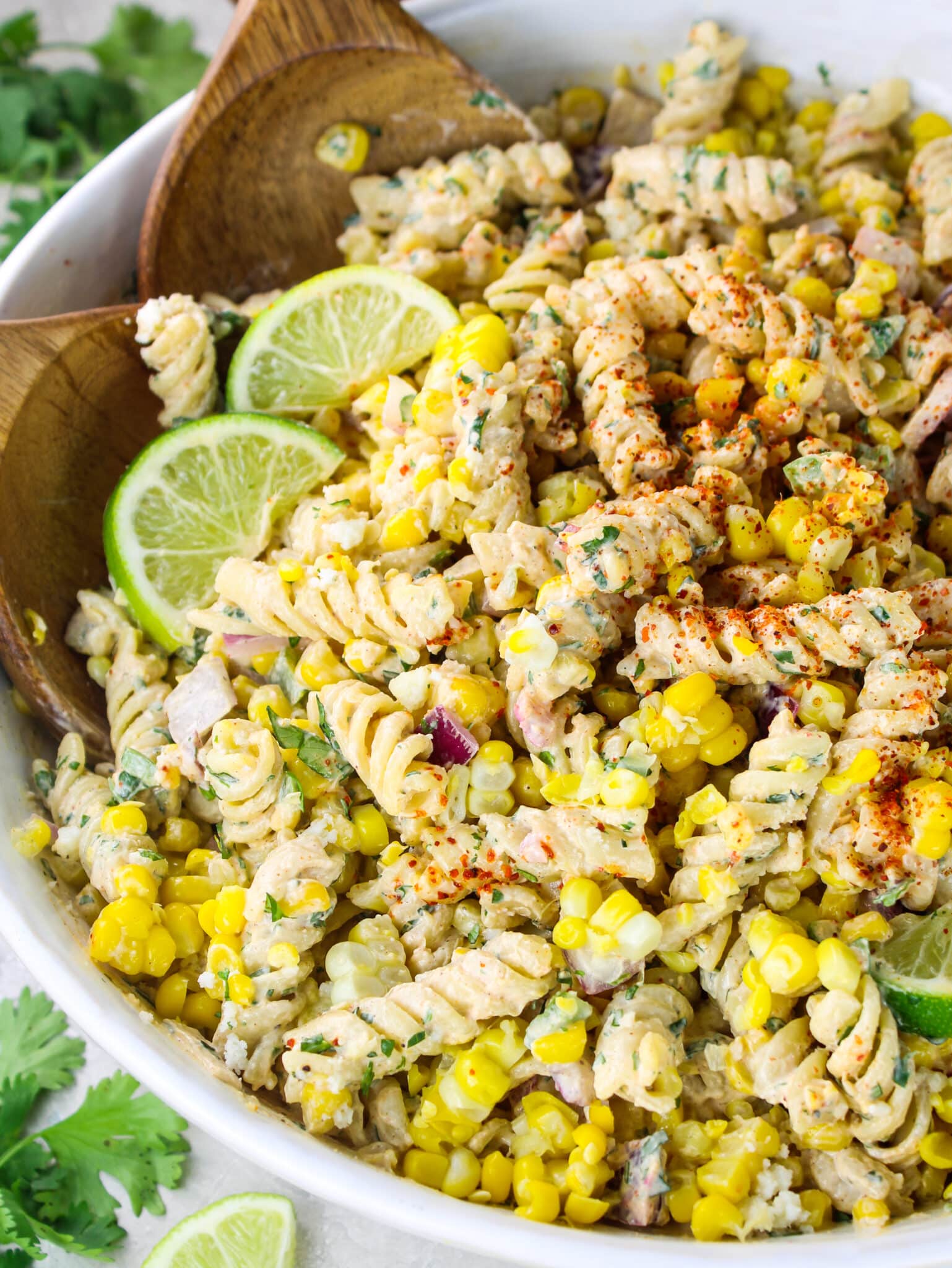 Partial bowl view of Mexican corn pasta salad with cotija cheese and jalapeño in the background