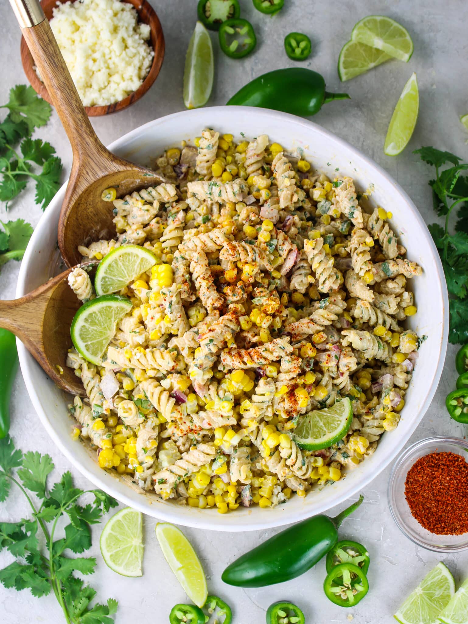 Overhead shot of Mexican street corn pasta salad garnished with lime, cotija, and chili powder, ready to serve